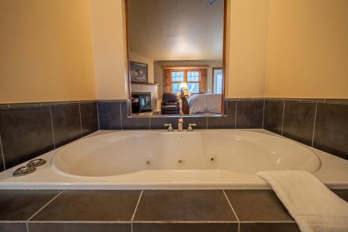 a large white tub in a bathroom with a mirror at Albergo Allegria Hotel & Breakfast Restaurant in Windham