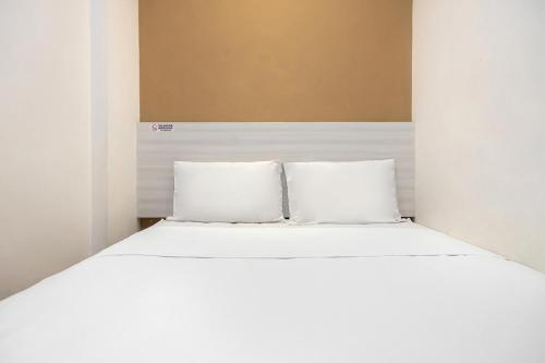1 cama blanca con 2 almohadas en una habitación en Twospaces Living at Kertajaya Residence, en Bagongsabrangan