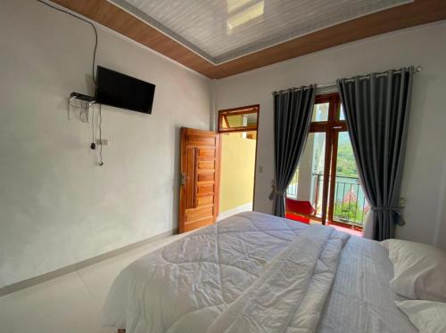 a bedroom with a bed and a tv and a window at Tama View in Tuk Tuk