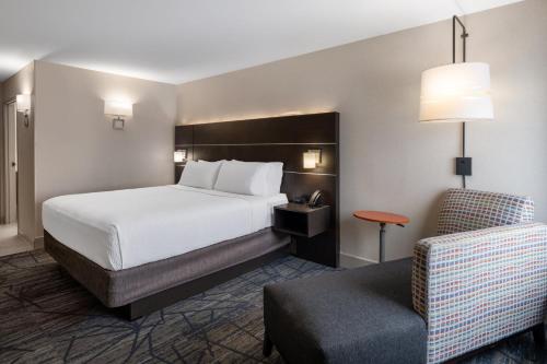 a hotel room with a bed and a chair at Holiday Inn Express Corydon, an IHG Hotel in Corydon