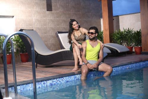 Ein Mann und eine Frau sitzen neben einem Pool in der Unterkunft Hotel Morning Glow in Digha