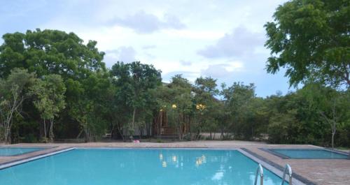 una piscina vacía con árboles en el fondo en Giman Free Beach Resort, en Pasikuda