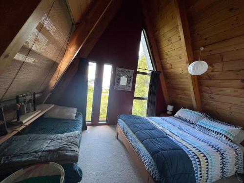 a bedroom with two beds in a wooden cabin at Pointy Bird, Tranquility, rejuvenating,pets welcome in Hamurana