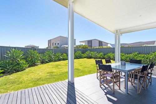 a patio with a table and chairs under a white umbrella at On Seascape in Sellicks Beach