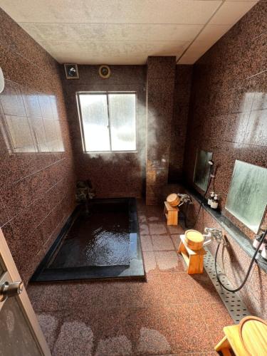 a bathroom with a tub and a shower with a toilet at Lodge Seizan in Nozawa Onsen