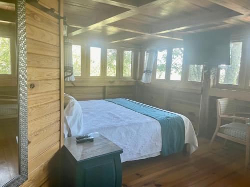 a bedroom with a bed and a table and windows at Cabañas el Chalet in Morelia