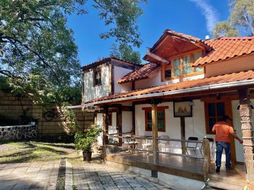 a man standing on the porch of a house at Cabañas el Chalet in Morelia