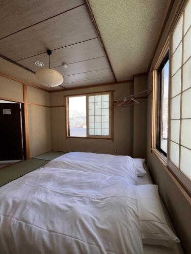 a large bed in a room with two windows at Lodge Seizan in Nozawa Onsen