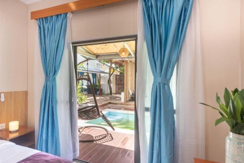 a bedroom with blue curtains and a swimming pool at Siargao Seasky Resort in Catagnan