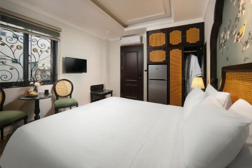 a bedroom with a white bed and a table and chairs at La Passion Hanoi Hotel & Spa in Hanoi