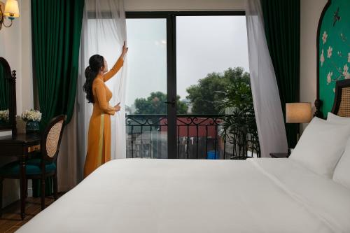 a woman looking out the window of a hotel room at La Passion Hanoi Hotel & Spa in Hanoi