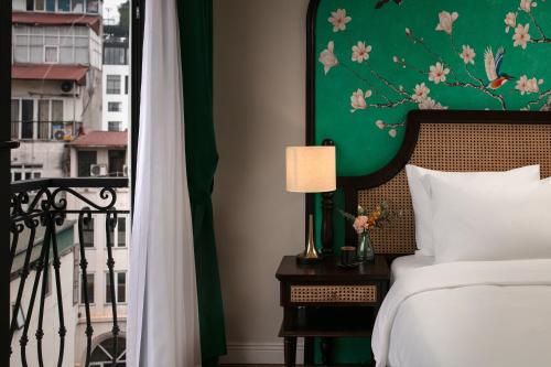 a bedroom with a bed and a green wall at La Passion Hanoi Hotel & Spa in Hanoi