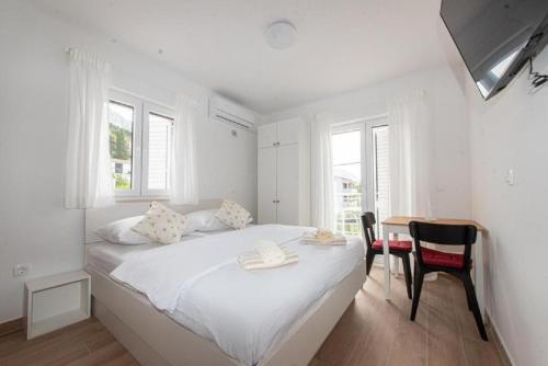 Habitación blanca con cama, escritorio y ventanas en Apartments Mir - close to beach, en Duće