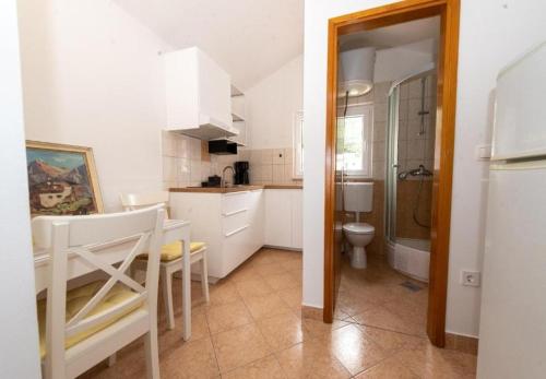 cocina con armarios blancos, mesa y sillas en Apartments Mir - close to beach, en Duće