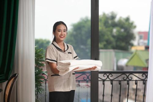 a woman standing on a balcony holding a towel at La Passion Hanoi Hotel & Spa in Hanoi