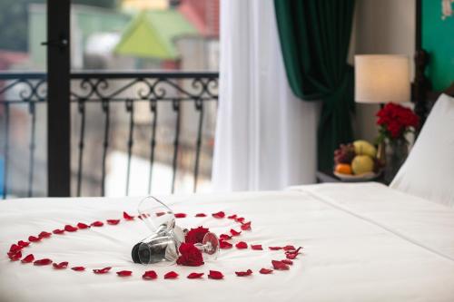 a white plate with red roses on a bed at La Passion Hanoi Hotel & Spa in Hanoi