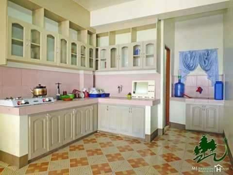 a kitchen with white cabinets and a tile floor at Mj Transient Homes in Baguio