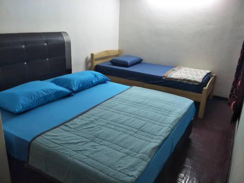 two beds in a room with blue pillows at Sharaa seaview Apartment in Port Dickson