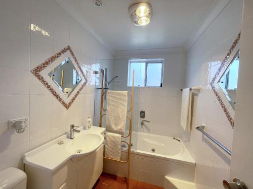 ein Badezimmer mit einem Waschbecken, einer Badewanne und einem WC in der Unterkunft Beachside Apartment Blackwoods Beach in Cronulla