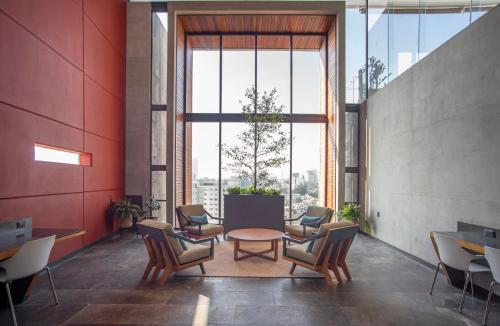 a room with chairs and a table and a large window at voco Guadalajara Neruda by IHG in Guadalajara