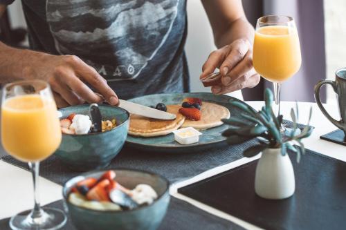 a person eating pancakes with fruit on a table with glasses of orange juice at Shutters-Waterfront-Private-at Little Blowhole in Kiama