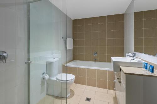 a bathroom with a toilet and a shower and a sink at Meriton Suites Broadbeach in Gold Coast
