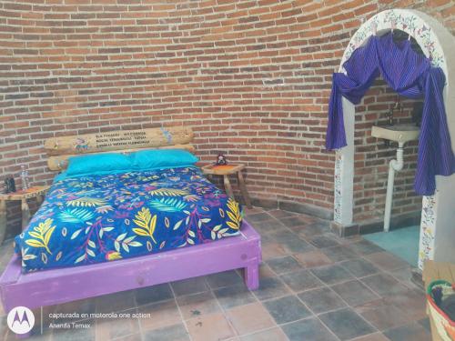 的住宿－Glamping temax，紫色床罩砖墙内的一张床位