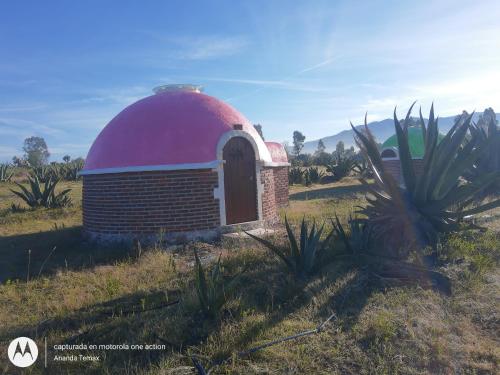 的住宿－Glamping temax，一块砖砌的建筑,在田野上用红色的圆顶