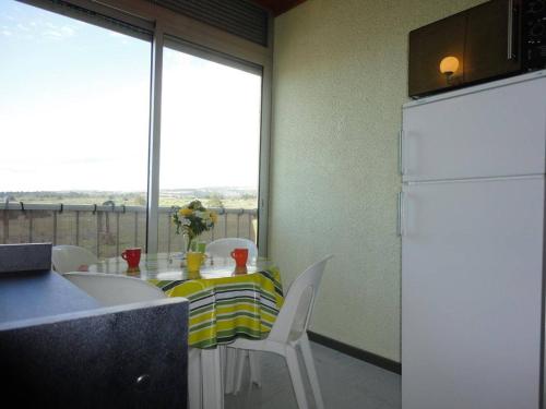 Il comprend une cuisine équipée d'une table avec des chaises et d'un réfrigérateur blanc. dans l'établissement Appartement 2P avec Mezzanine, Piscine et Tennis, 800m de la Plage – 6 Couchages – St Pierre la Mer - FR-1-229D-267, à Saint Pierre La Mer