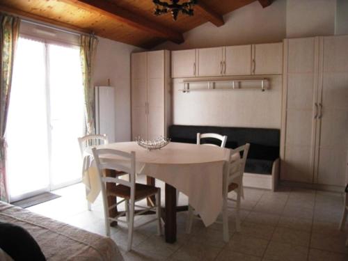 une salle à manger avec une table et des chaises blanches dans l'établissement Maison à 300m de la plage avec jardin clos, terrasse, BBQ et 2 chambres - FR-1-224B-515, à LʼÉpine