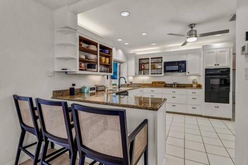 a kitchen with white cabinets and a counter with chairs at House w/ heated pool in Naples 5 min to beach in Naples