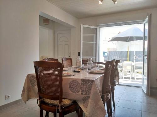 - une salle à manger avec une table, des chaises et un parasol dans l'établissement Maison rénovée près de la plage avec jardin clos, 300m de la mer, La Guérinière - FR-1-224B-69, à La Guérinière