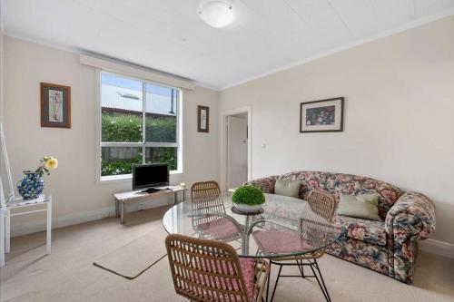 ein Wohnzimmer mit einem Sofa und einem Tisch in der Unterkunft Beach view Rippleside Cottage in Geelong West