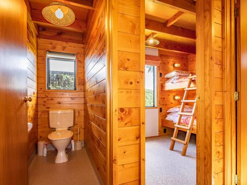a log cabin bathroom with a toilet and bunk beds at Rakau - National Park Holiday Home in National Park