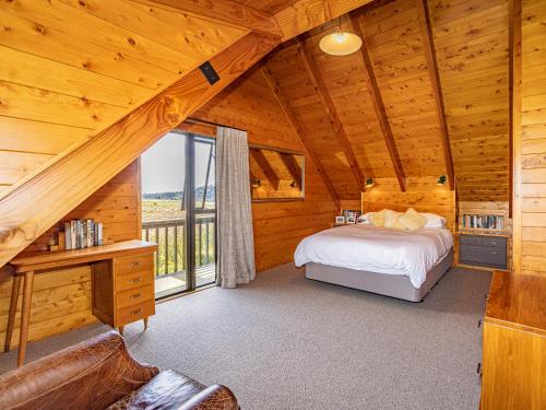 1 dormitorio en una cabaña de madera con cama y ventana en Rakau - National Park Holiday Home en National Park
