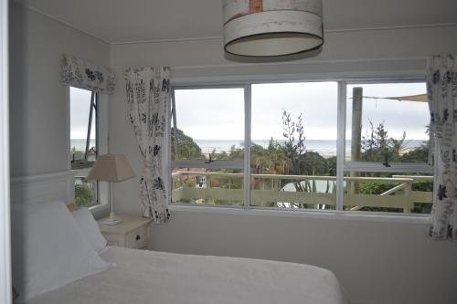 een slaapkamer met een bed en een groot raam bij AHIPARA GOLDENSANDs in Ahipara