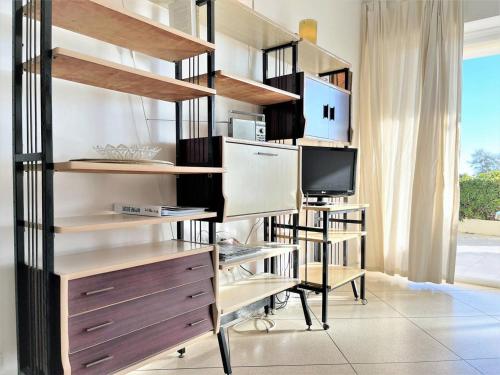 Cette chambre dispose d'étagères, d'un bureau et d'une télévision. dans l'établissement Appartement T2 avec Parking au Lavandou, Pieds dans l'Eau - FR-1-251-210, au Lavandou