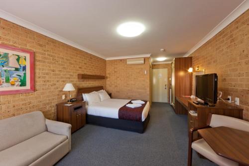 a hotel room with a bed and a couch at Tamworth Motor Inn & Cabins in Tamworth