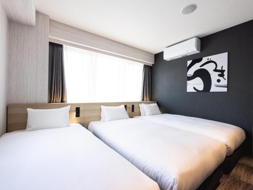 two beds in a room with white sheets at La'gent Hotel Kyoto Nijo in Kyoto