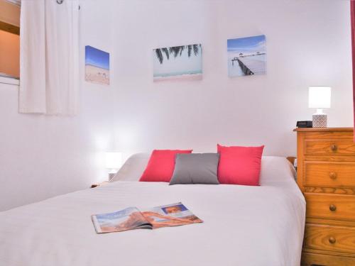 une chambre avec un lit blanc avec des oreillers rouges dans l'établissement Appartement climatisé avec balcon et parking privatif, à 100m de la plage - Le Lavandou - FR-1-251-352, au Lavandou