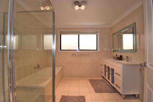 a bathroom with a shower and a tub and a sink at Holiday Home in Koonawarra in Dapto