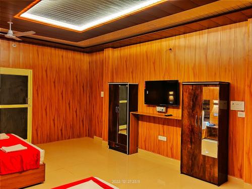 a living room with a television and wooden walls at Kyarki Resort in Rishīkesh