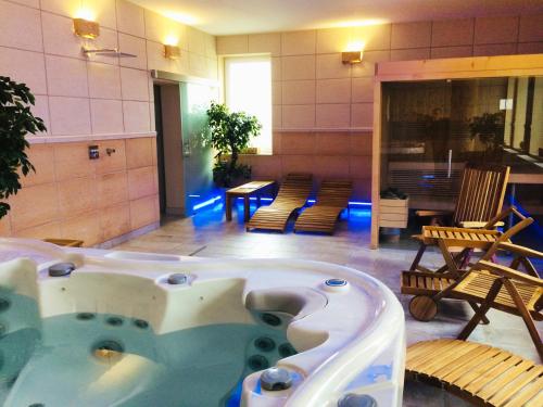 une grande baignoire jacuzzi dans une pièce avec des chaises dans l'établissement Hotel Churáňov, à Stachy