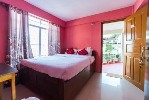 - une chambre avec des murs rouges et un lit avec des oreillers rouges dans l'établissement Pink Guest House, à Shillong