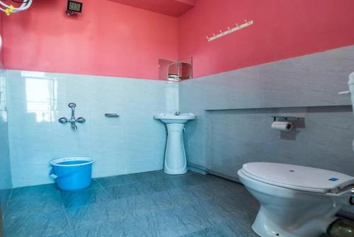 La salle de bains est pourvue de toilettes blanches et d'un mur rouge. dans l'établissement Pink Guest House, à Shillong