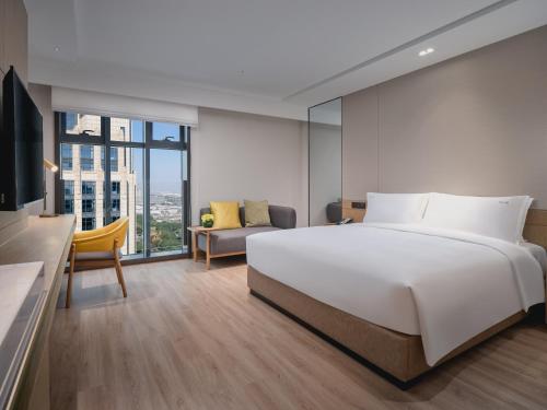 a bedroom with a large white bed and a couch at Holiday Inn & Suites Kunshan Huaqiao by IHG - F1 Racing Preferred Hotel in Kunshan