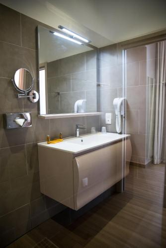 a bathroom with a sink and a mirror at Hôtel CASABELLA Cannes Mouans Sartoux in Mouans-Sartoux