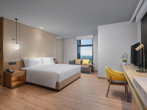 a hotel room with a white bed and a desk at Holiday Inn & Suites Kunshan Huaqiao by IHG - F1 Racing Preferred Hotel in Kunshan