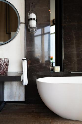 a bathroom with a large white tub and a mirror at Jumeirah Guangzhou - Complimentary Shuttle Bus to Canton Fair Complex in Guangzhou