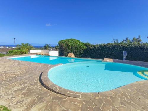 a large swimming pool with blue water in a yard at SunBliss Appartement in Saint-Gilles les Bains